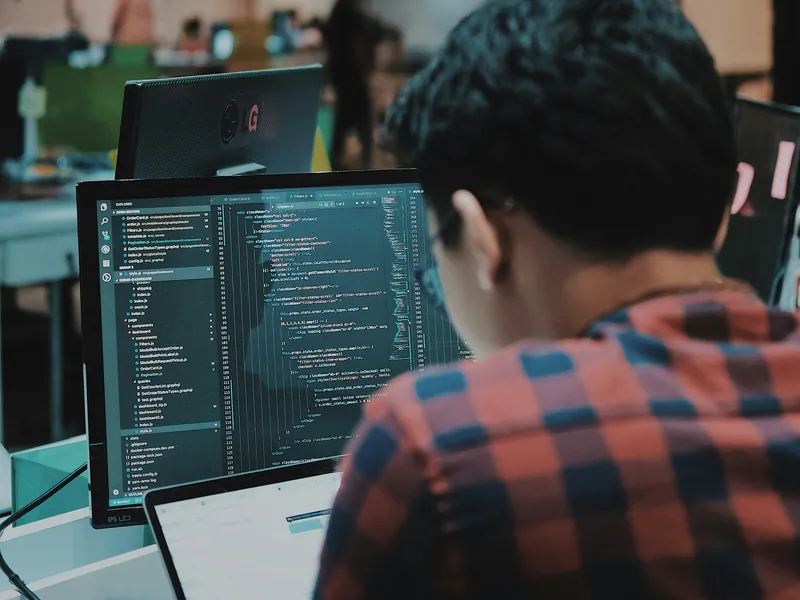 Développeur de dos devant un écran affichant du code